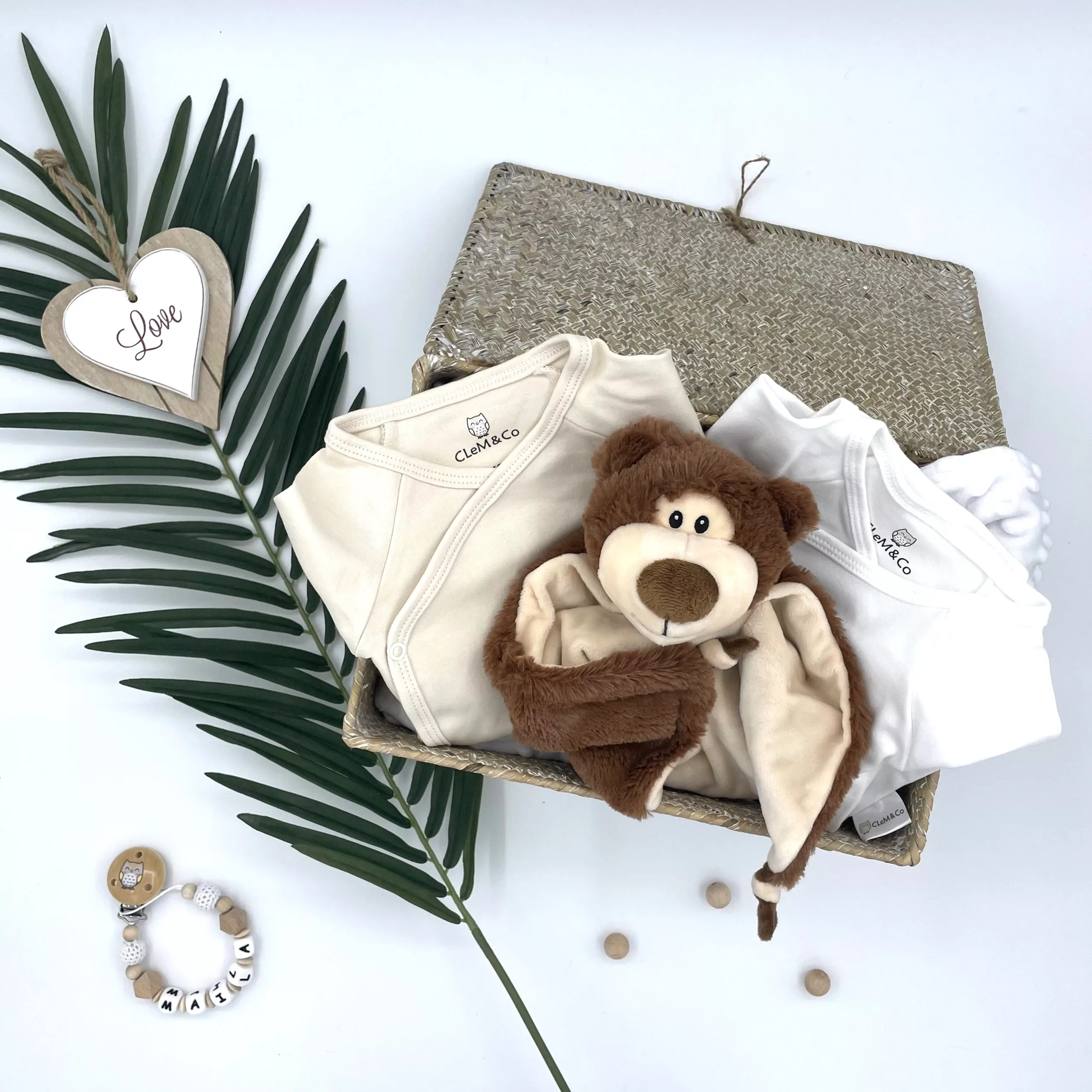 Sélection d'essentiels pour bébé : chaîne à lolette, doudou nounours, body et pyjama doux pour des nuits paisibles